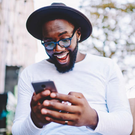 Ein Kunde schaut erfreut auf sein Smartphone